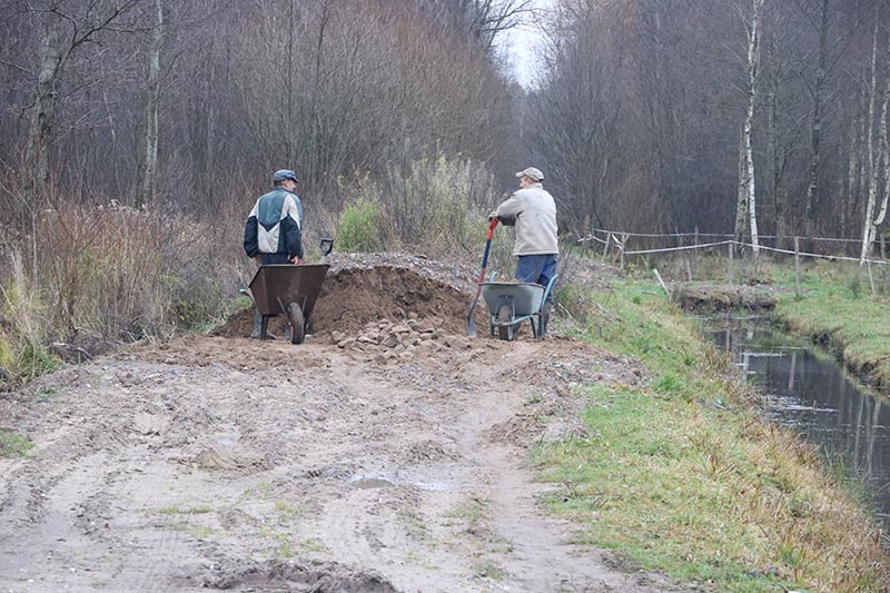 Pelkininkai pluša, tvarkydami potvynio nuplautą kelią. Akmenys, žvyras kraunami į karučius ir išpilami, taip aukštinant gatvę. Deniso NIKITENKOS nuotr.