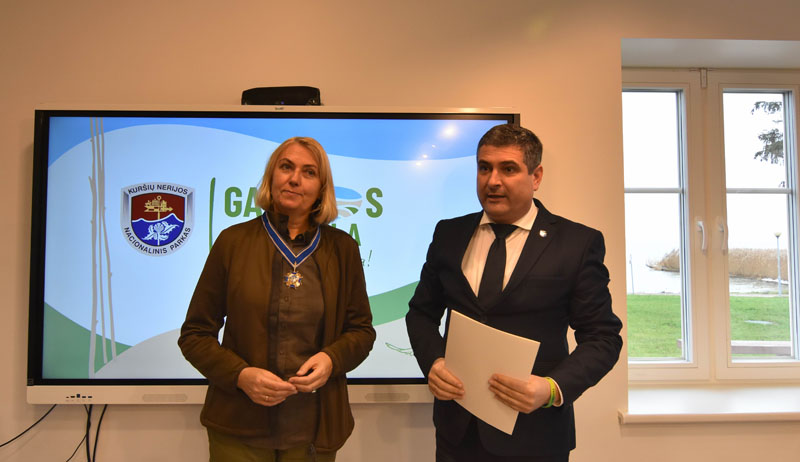 PAGERBĖ. Mokyklos pristatymo bendruomenei metu meras Darius Jasaitis Kuršių nerijos nacionalinio parko direkcijos vadovei, Neringos savivaldybės tarybos narei Aušrai Feser įteikė Neringos savivaldybės Garbės ženklą. Neringos savivaldybės nuotr.