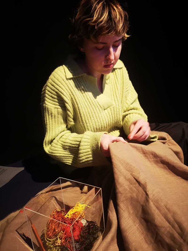 Mila Kostiana savo kūrinyje „Šaknys“ kviečia lankytojus dalyvauti grupiniame sapnų siuvinėjimo projekte. 