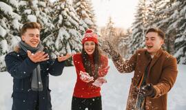 Trys jauni žmonės džiaugiasi žiemos malonumais