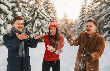 Trys jauni žmonės džiaugiasi žiemos malonumais