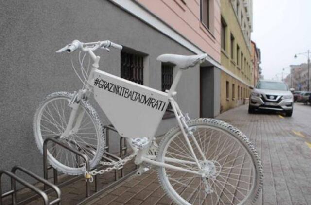 Baltas dviratis keliauja per miestą