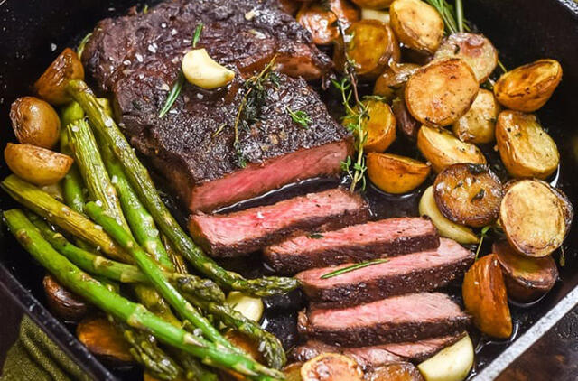 Keptuvėje keptas česnakinis sviesto kepsnys su traškiomis bulvėmis ir šparagais